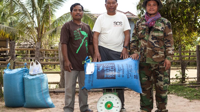 Three local men holding a bag of rice